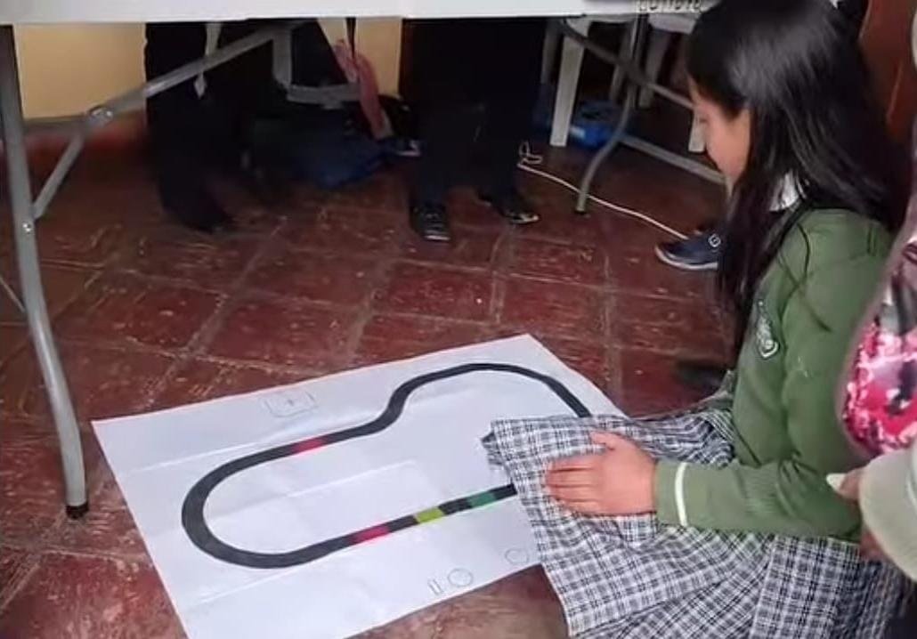 Estudiante trabajando junto a una pista de robótica educativa