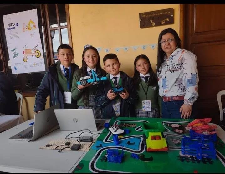 Equipo de estudiantes y docente presentando robots y materiales tecnológicos